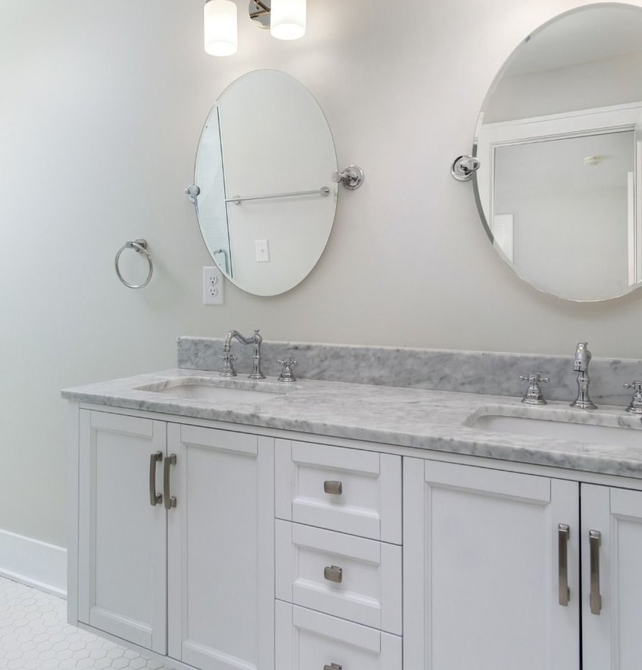 Bathroom after: white double vanity with marble top and two oval mirrors