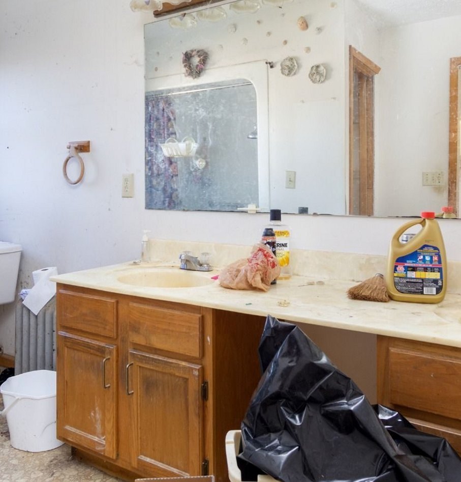 Bathroom before: dated oak vanity, cluttered counter and a large old mirror