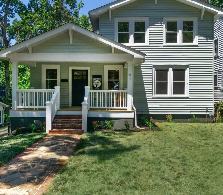 Craftsman house after: gray siding, white porch railings, a stone walk and a green lawn