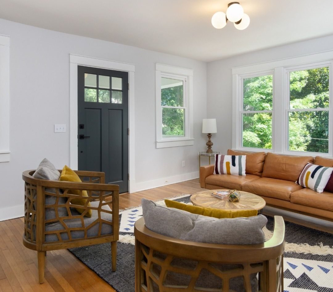 Living room after: finished walls, hardwood floor, a dark front door and new furniture