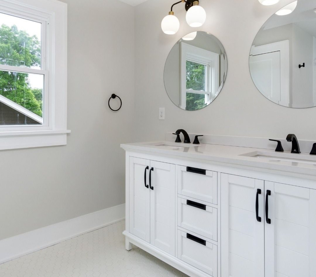 Primary bath after: white double vanity, round mirrors and globe lights