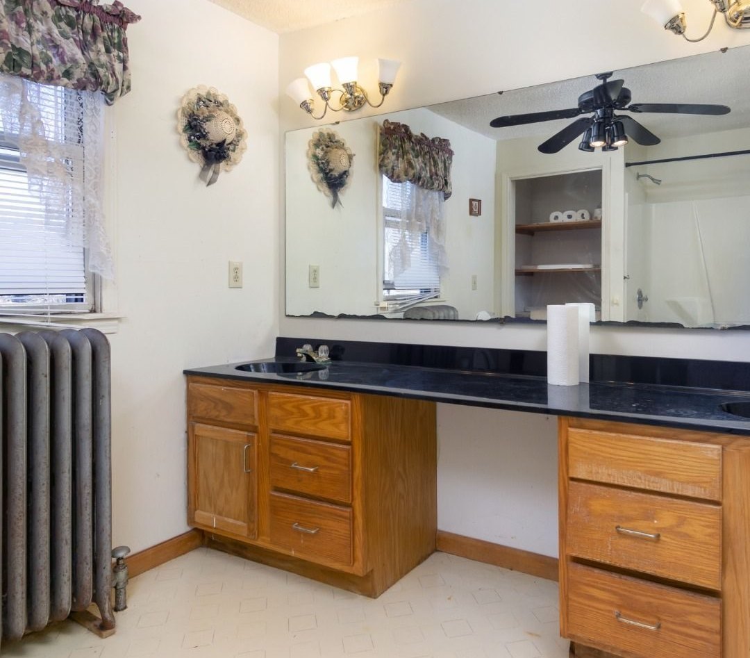 Primary bath before: dark-topped oak vanity and an old radiator