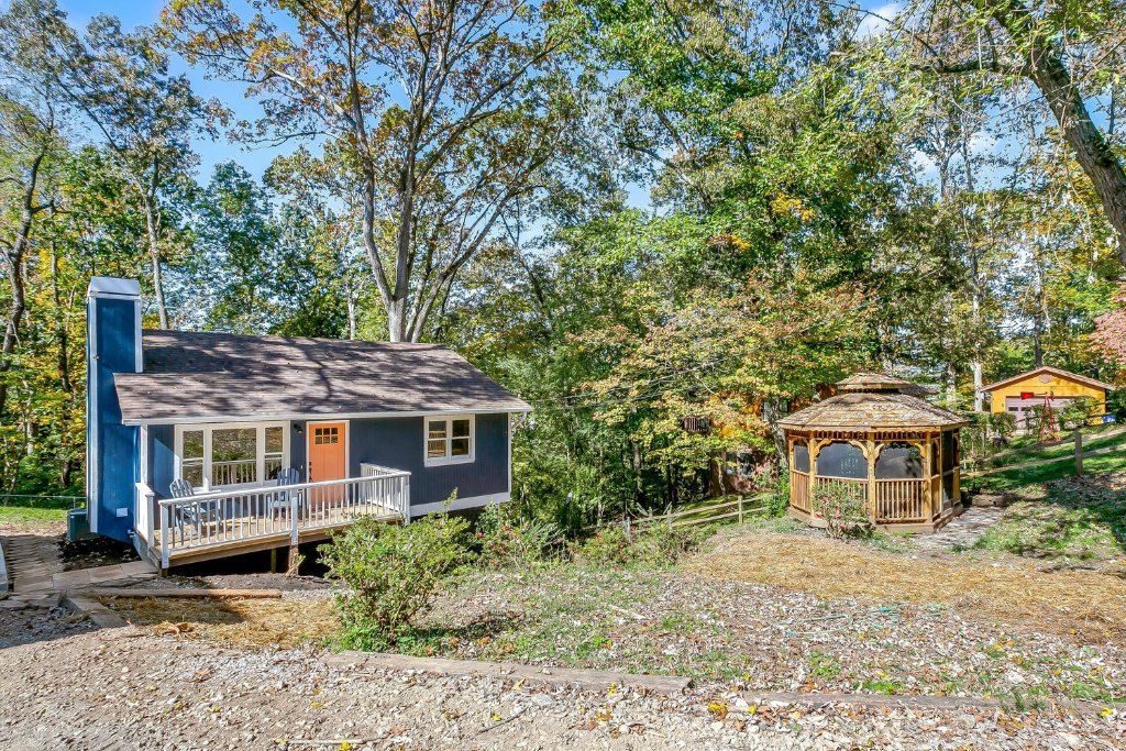 Navy house with an orange door and a wooden gazebo in the yard