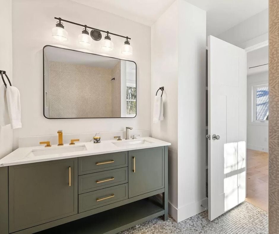 Green double vanity with brass fixtures and a black-framed mirror