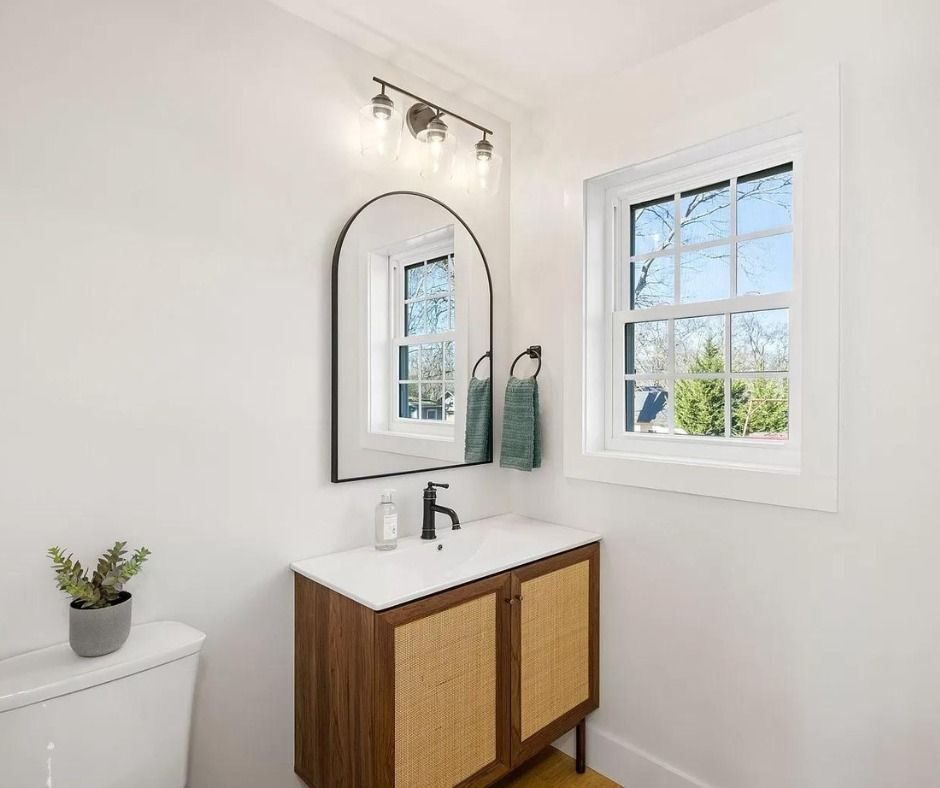 Small bathroom with a wood and cane vanity and an arched mirror