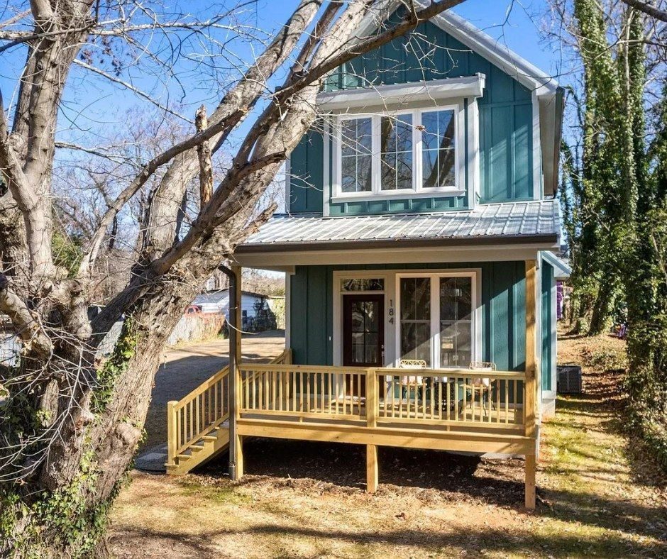 Teal two-story home with a wood front porch and metal roof