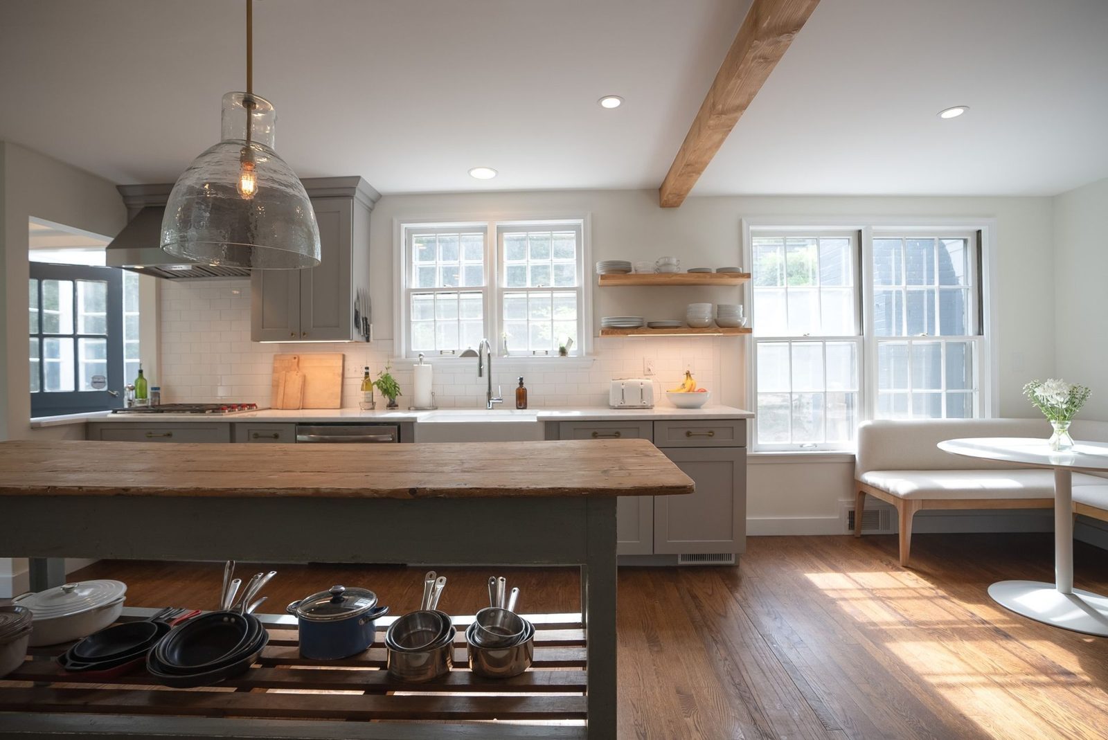 Open kitchen with a timber beam, glass pendant and a wood-topped island