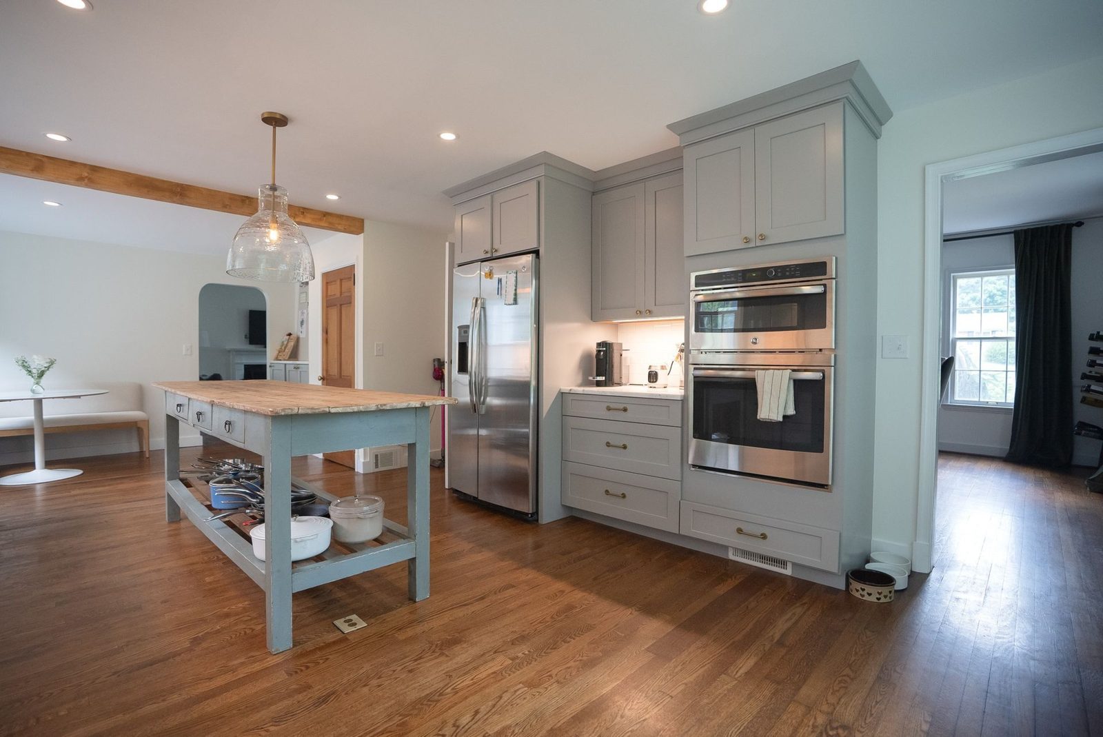 Finished open kitchen with a blue-gray island, wood floors and stainless appliances