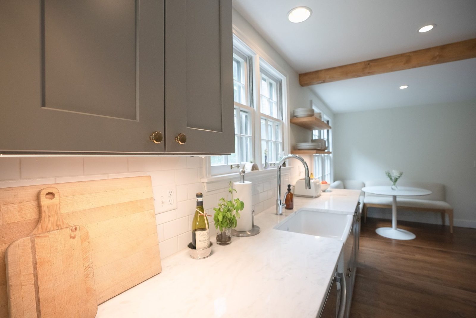 Kitchen counter with open wood shelving, white tile and a window