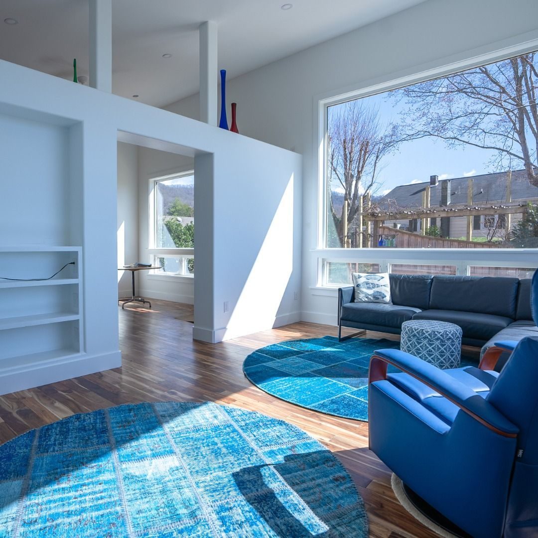 Living room with built-in shelving, a blue rug and a large picture window