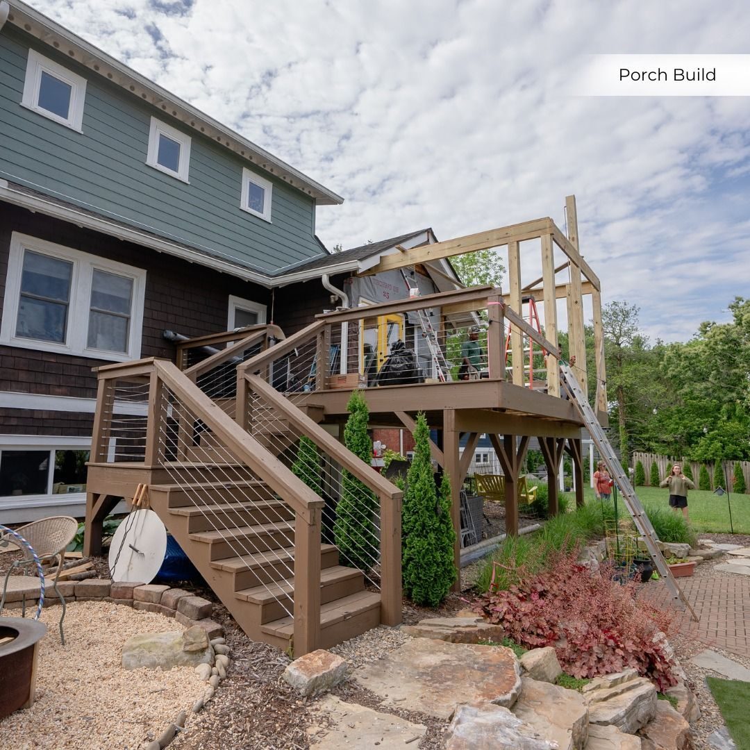Multi-level deck with stairs and cable railings behind a two-story house