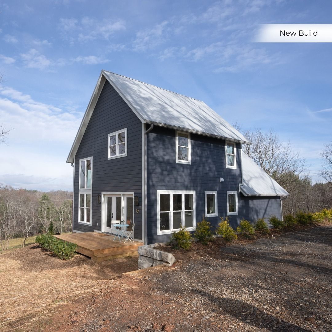 Dark blue two-story new build with white trim on a hillside