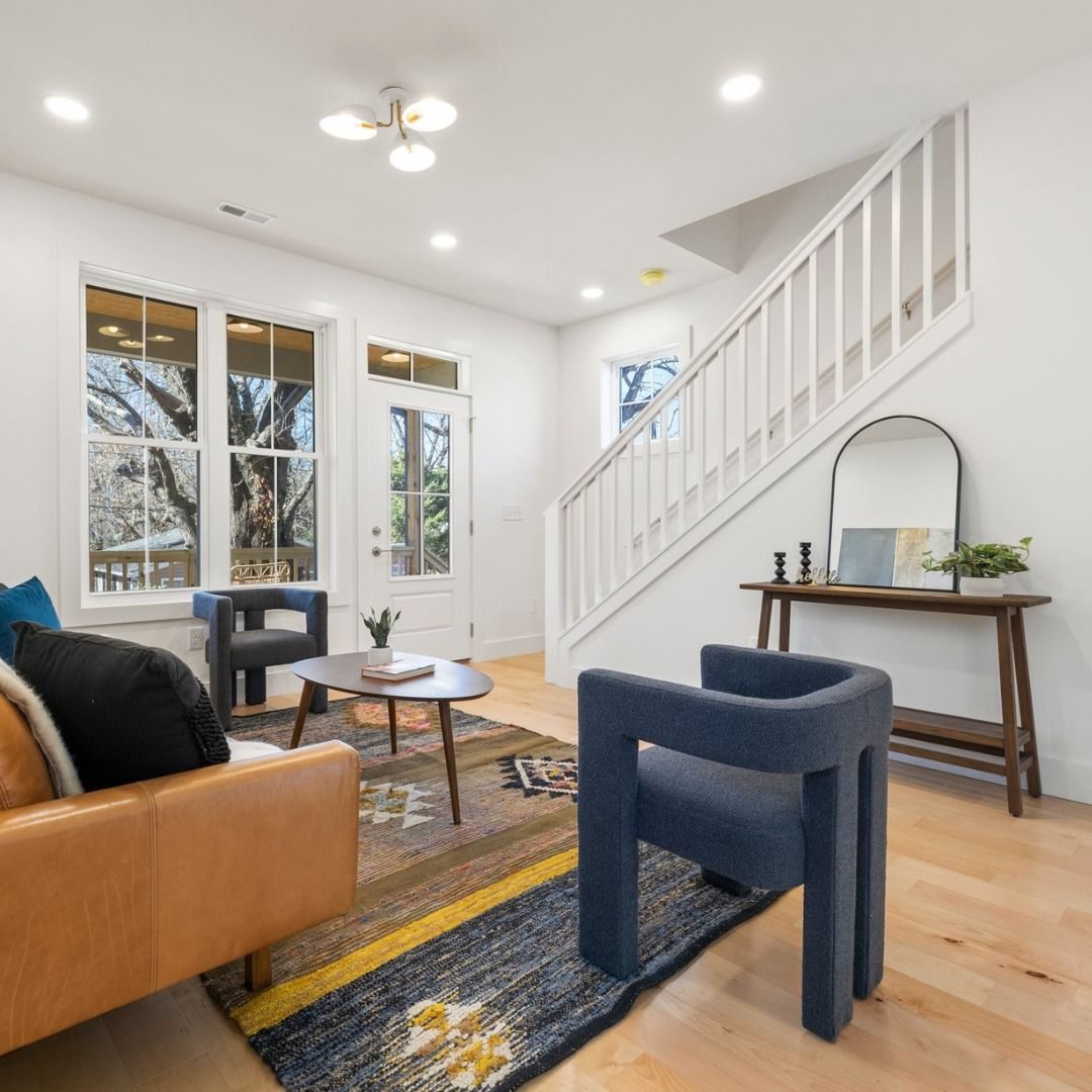 Bright living room with a leather sofa, sculptural chairs and a white staircase