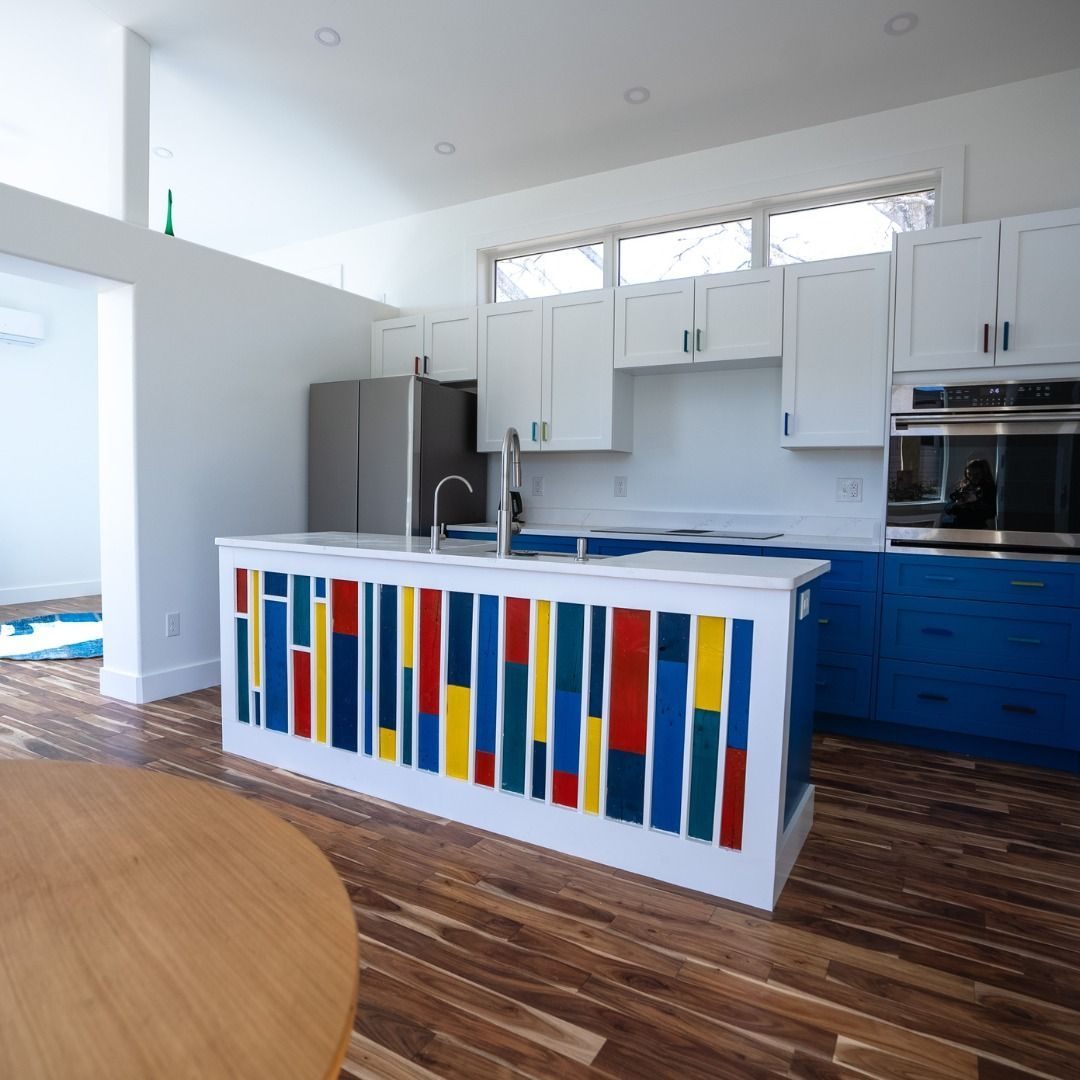 Kitchen island faced in bright colored panels with blue base cabinets